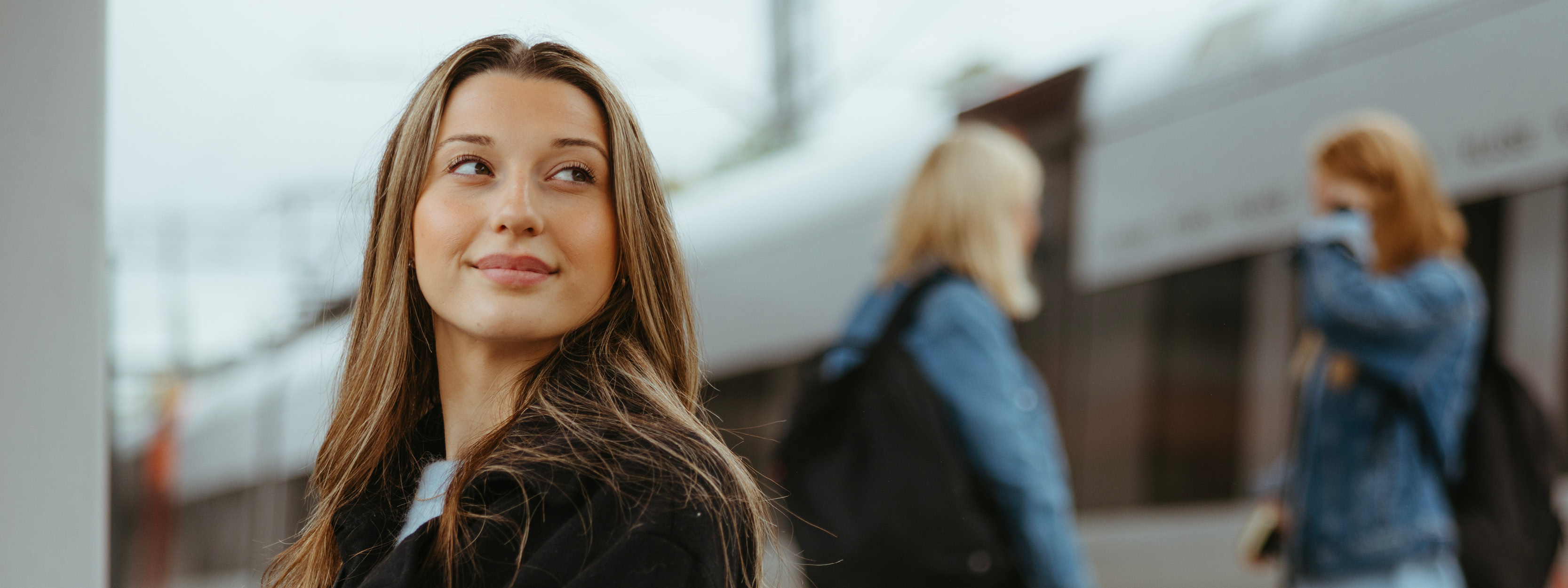 Kvinna som ler och tittar snett bort. I bakgrunden syns ett tåg.