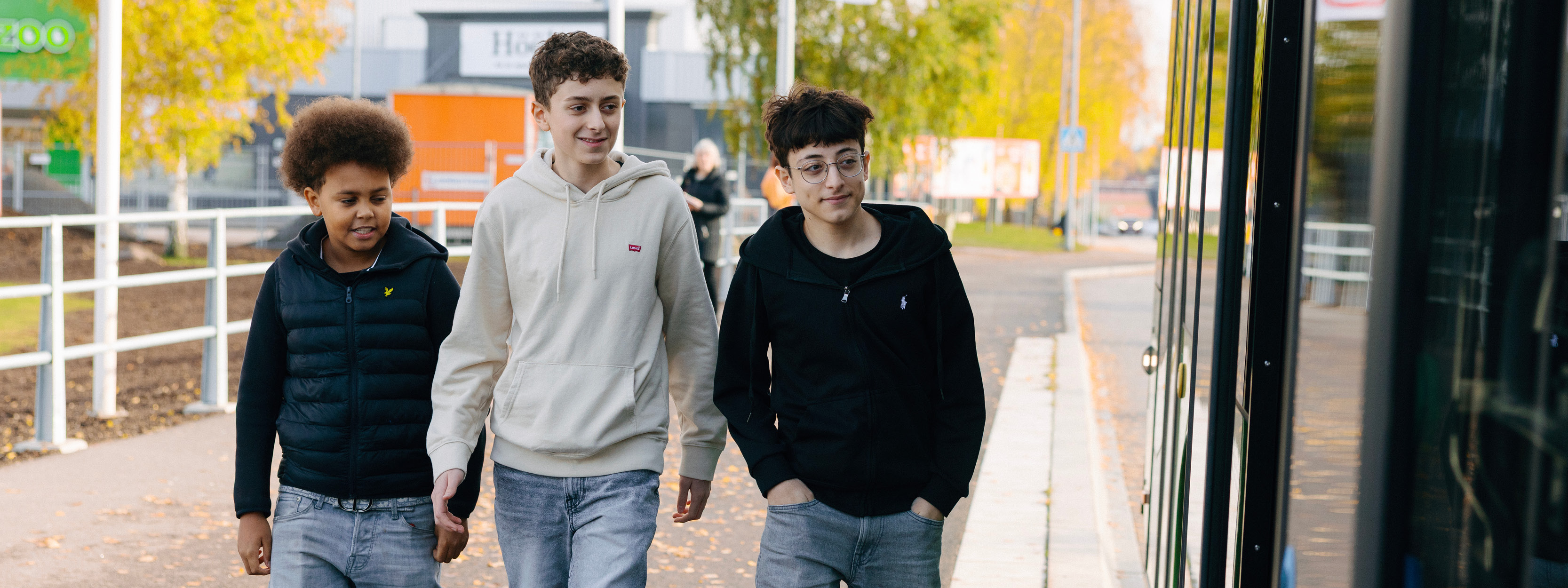 Tre killar går utmed en buss.