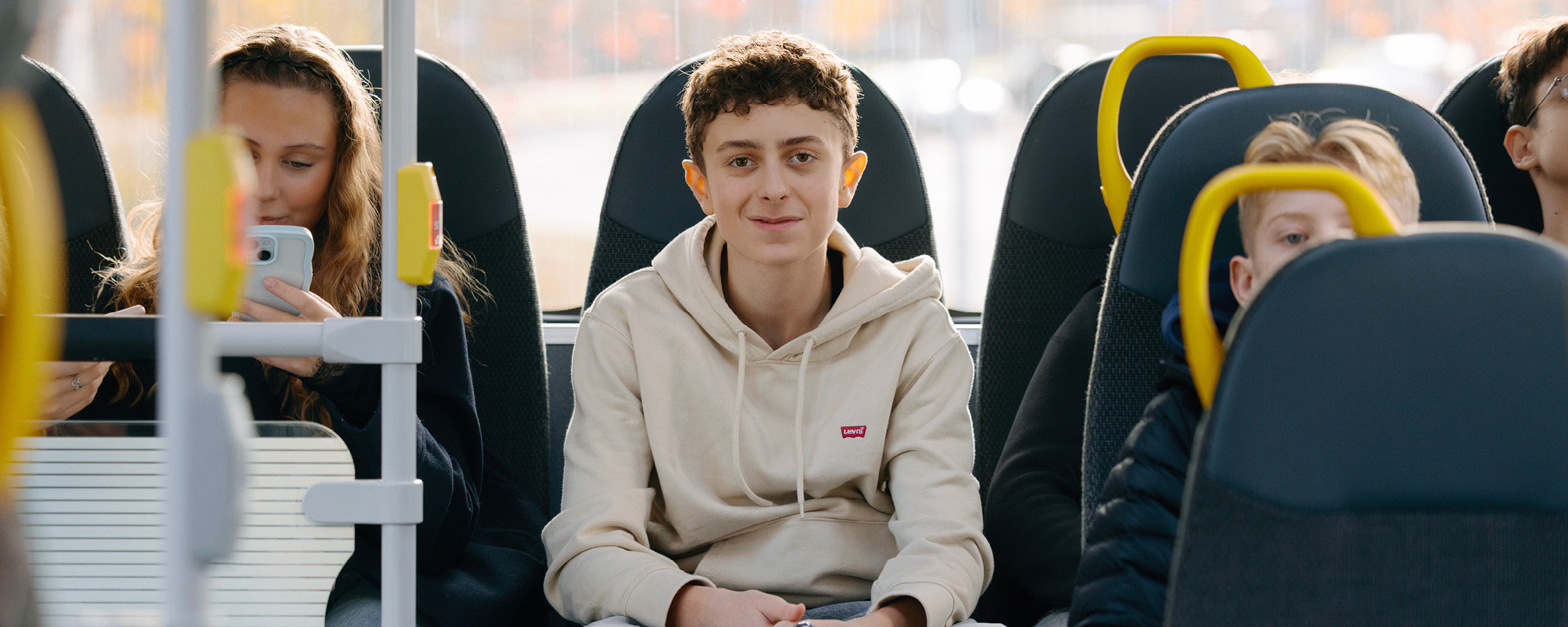 Kille sitter längst bak i en buss. Han ler. 