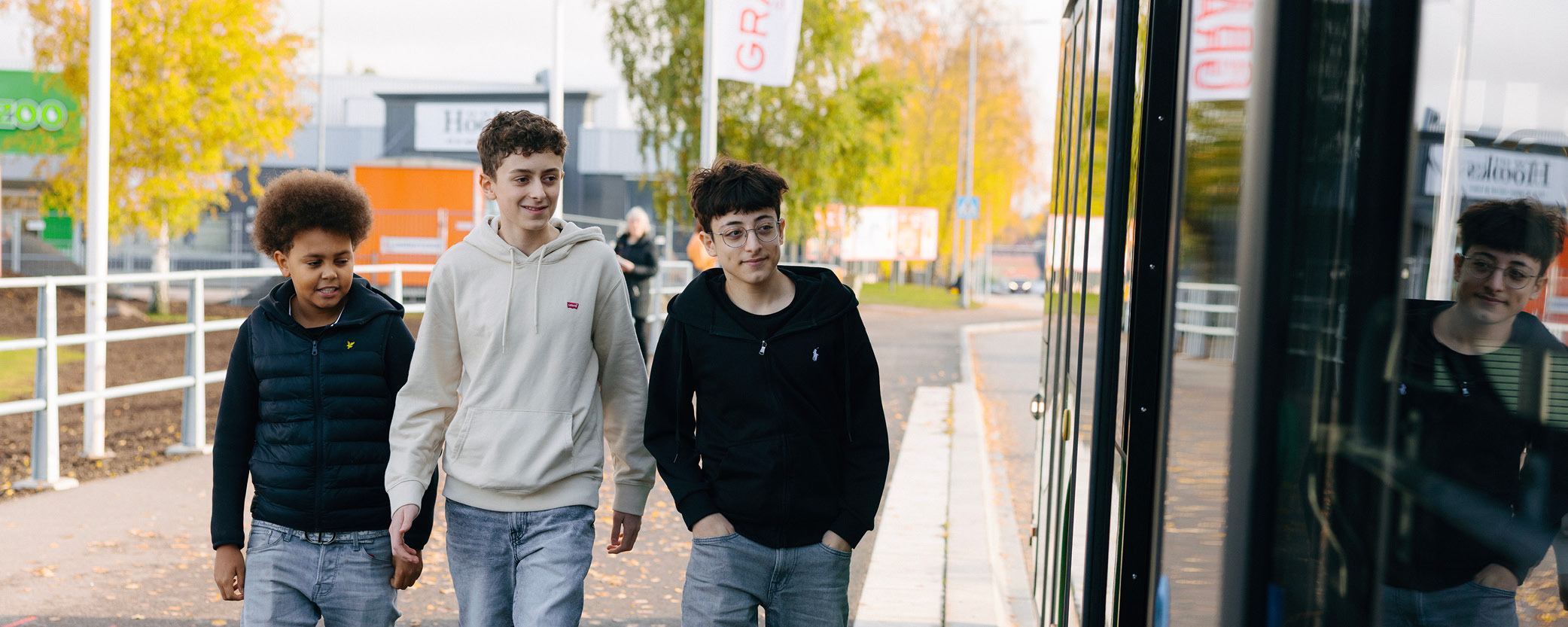 Tre killar går utmed en buss.