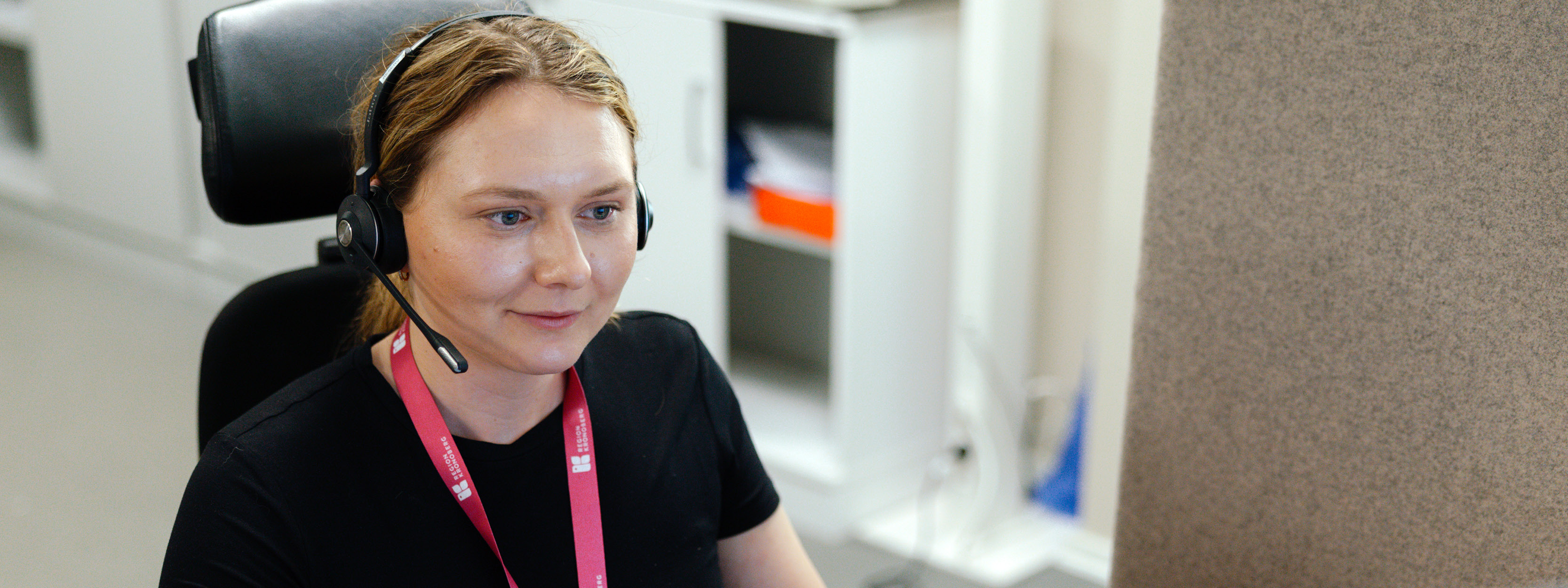 en tjej jobbar på serviceresor. sitter med ett headset och tar ett samtal.