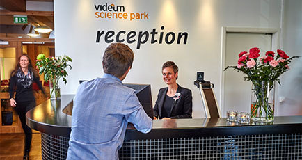 Bild på glada människor i en reception där receptionisten använder en MagniLink Pro.
