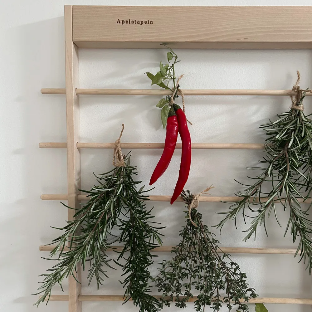 Apelstapeln hänger på väggen med färska kryddor och chili