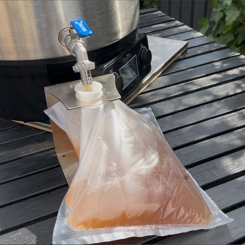 En 3-liters BIB-pose fyldes med varm æblejuice og holdes på plads af holderen for nem påfyldning