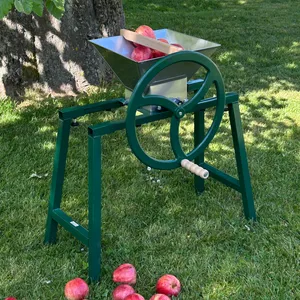 Käsikäyttöisen Hedelmämurskain 9L, jossa on kiinnitetyt ja nurmikolle sijoitetut ulokkeet.