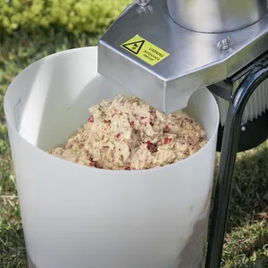 En fruktmassa bestående av krossade äpplen kommer ut från munstycket på en elektrisk fruktkross