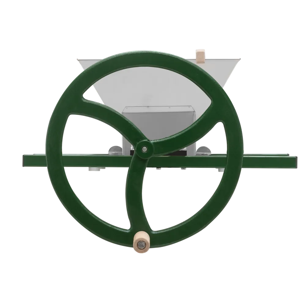 En manuell fruktkross från ett sidoperspektiv där det stora vevhjulet med handtag syns framför tratten