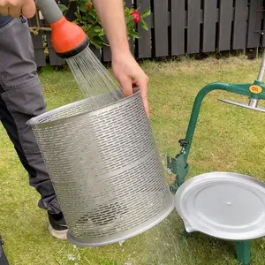 Rengöring av en cylinderformad presskorg med hjälp av en vattenslang utomhus på gräsmattan