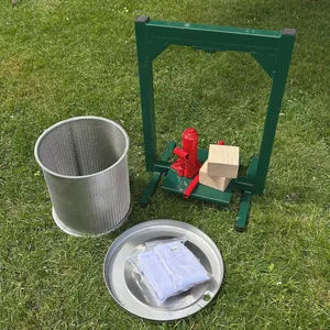 Hydraulisk fruktpress med tillhörande delar står utplacerade på en gräsmatta