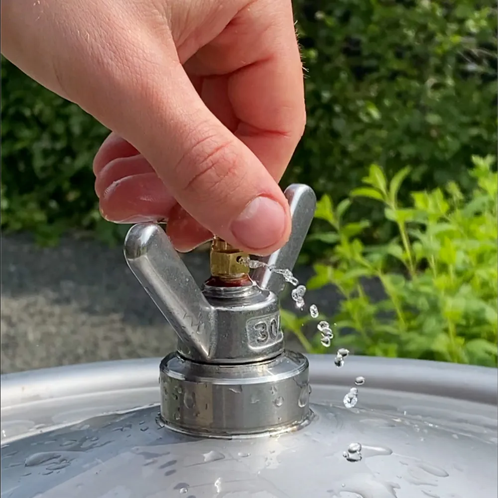 En hand justerar luftnivån med ventilen på en hydropress när membranet fylls med vatten