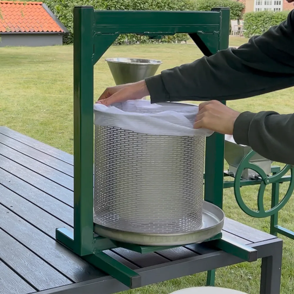 Filterduk är placerad i en presskrog och fylls med fruktkross för att pressa fruktmassan till must 