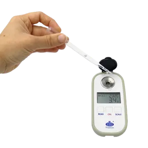 En hånd holder pipetten og slipper væske inn i refraktometeret