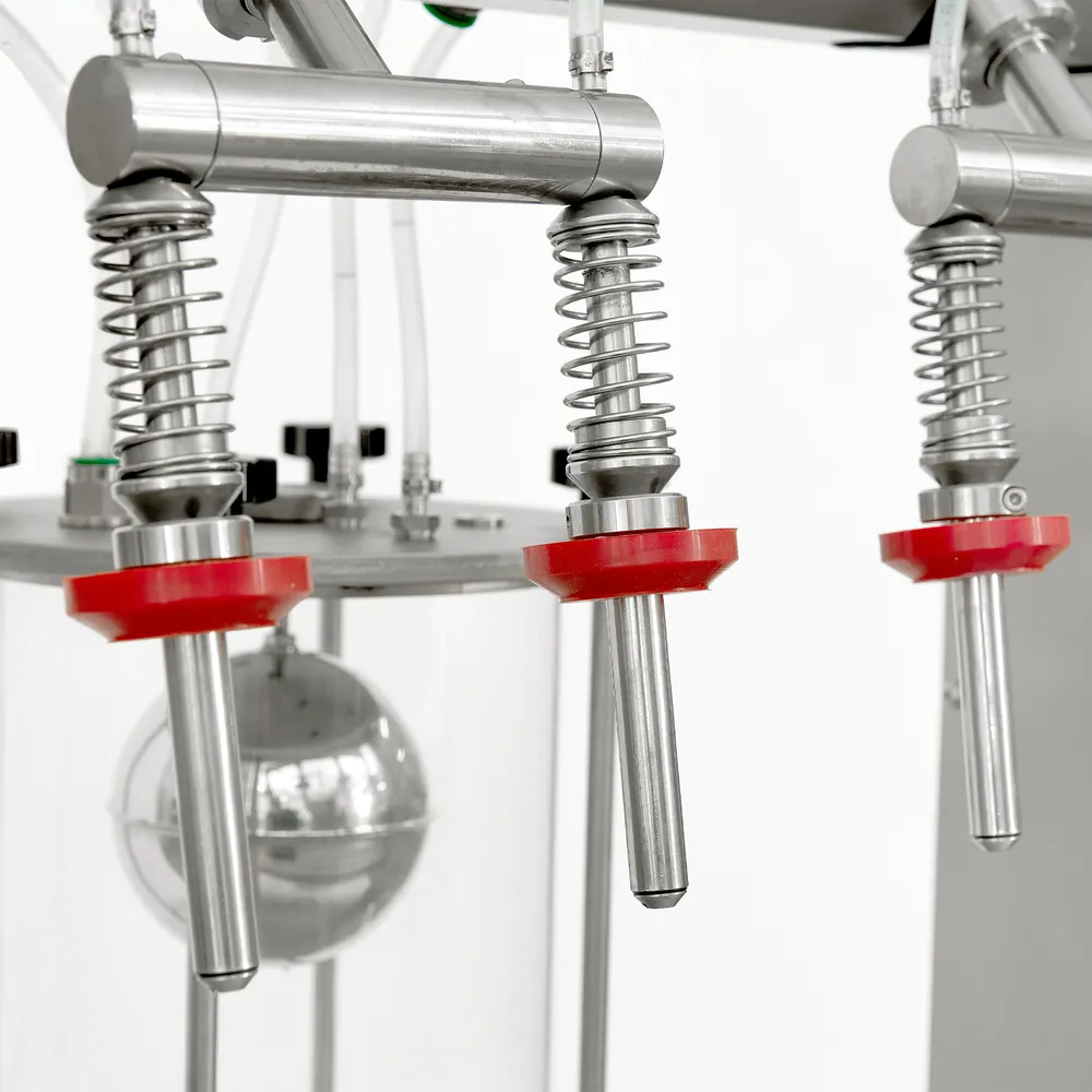 Närbild på maskinens 4 fyllnadsmunstycken, tillverkade i rostfritt stål med röda detaljer