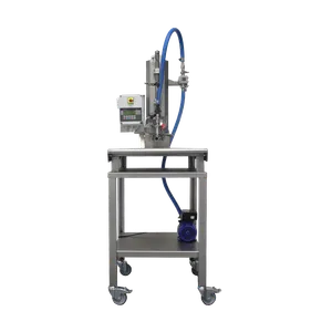 Maskinen sytår på ett bord av rostfritt stål med svängbara hjul, på bordets hylla sitter kompressor och pump kopplat till maskinen.