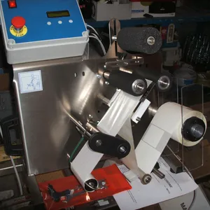 Billede af en etiketteringsmaskine med blå detaljer, hvor en rulle etiketter drejer rundt