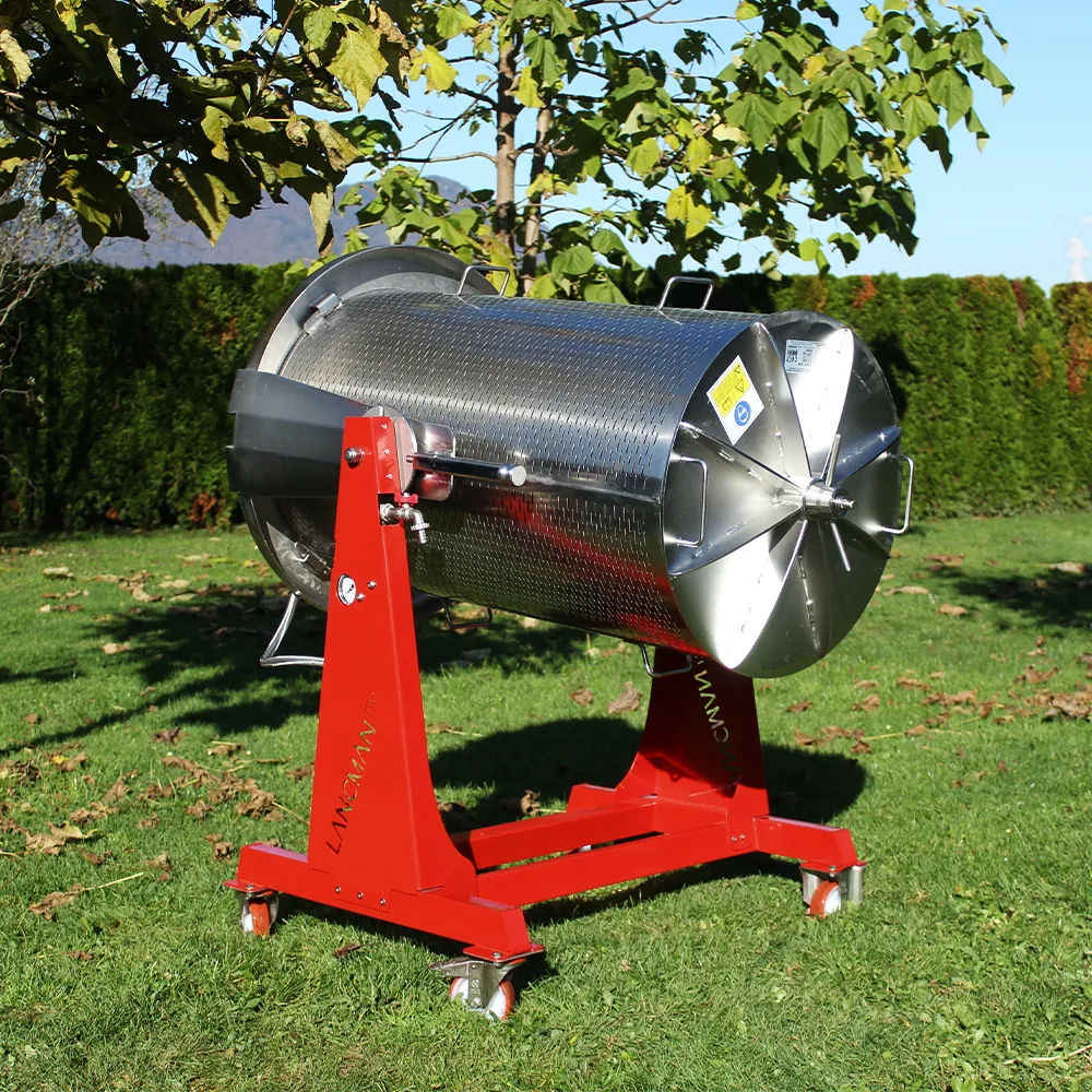 Hydropress i rostfritt stål med rödlackerad ram står placerad på en gräsmatta