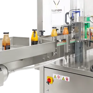 Glassflasker fylt med juice og merket kommer ut av maskinen