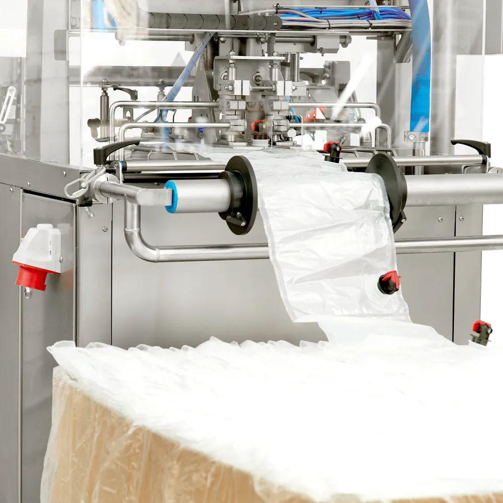 På baksidan av bag-in-box fyllaren står en pall med bag-in-box påsar som matas in i maskinen.