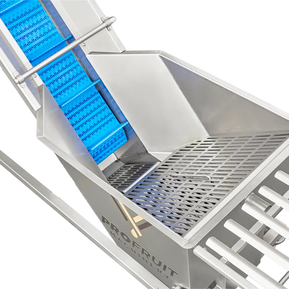 Opsamlingsbeholder i rustfrit stål med perforeret plade i bunden er placeret i begyndelsen af transportbåndet