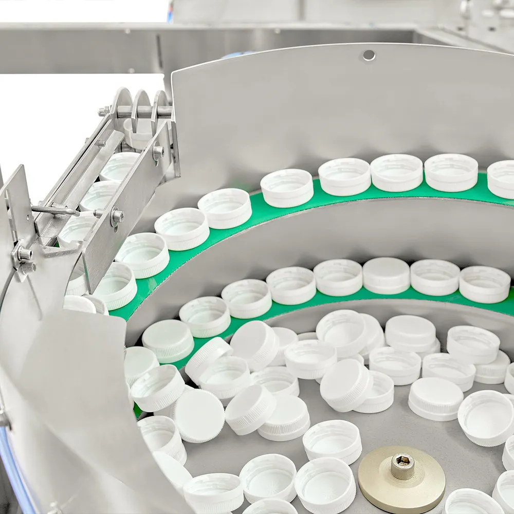 Roterende oppsamling og sortering av kapsler og lokk for forsegling av flaskene