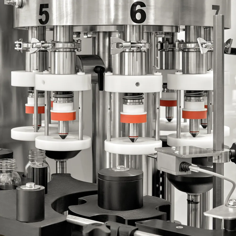 Roterende bord fører flaskene gjennom fyllestasjonen og forseglingsstasjonen i maskinen