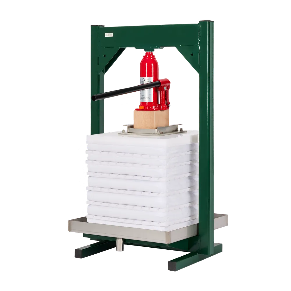 Hydraulisk ballepresse i grønnlakkert stål med hvite presseplater og rød jekk for pressing av frukt