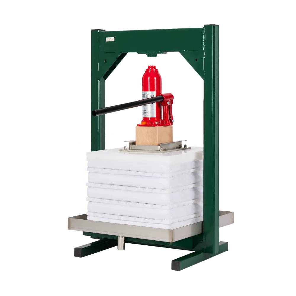 Hydraulisk presse i grønnlakkert stål med hvite presseplater og rød jekk for pressing av frukt