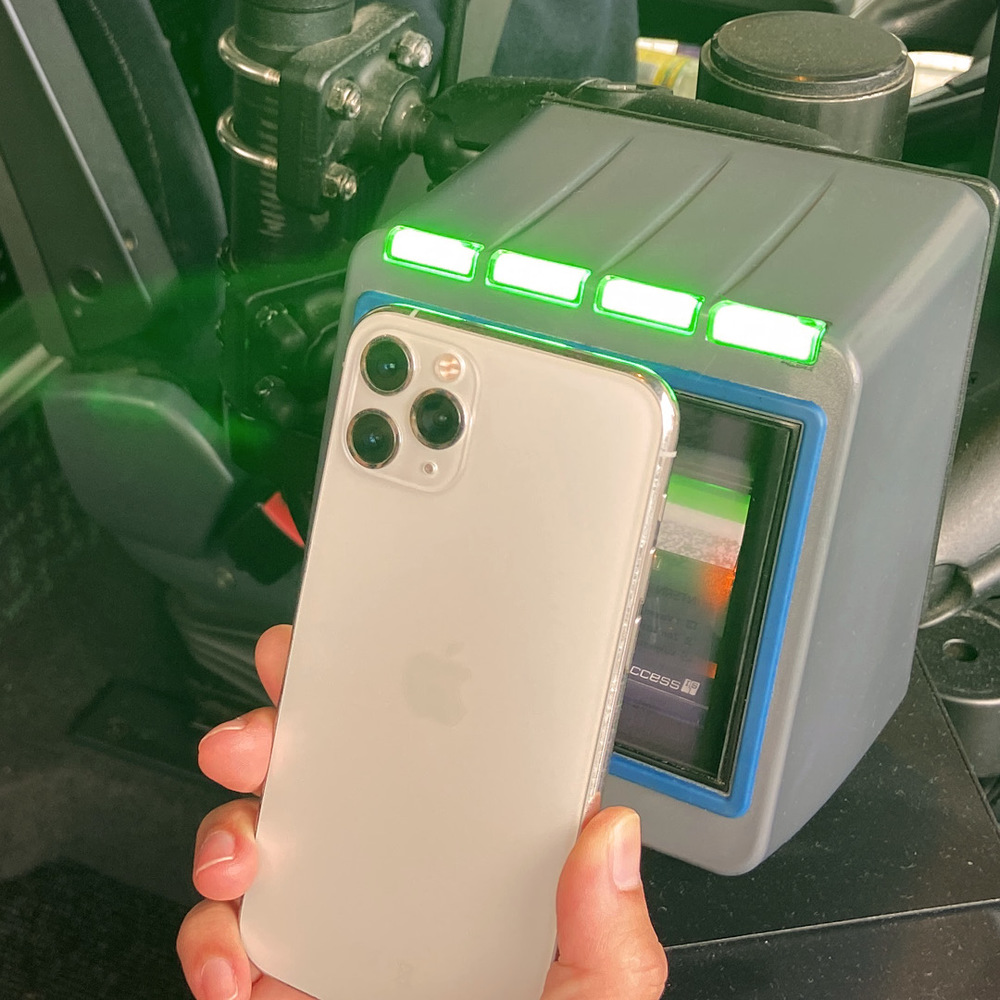 En mobiltelefon som hålls mot en biljettläsare. Biljettläsaren lyser grönt.