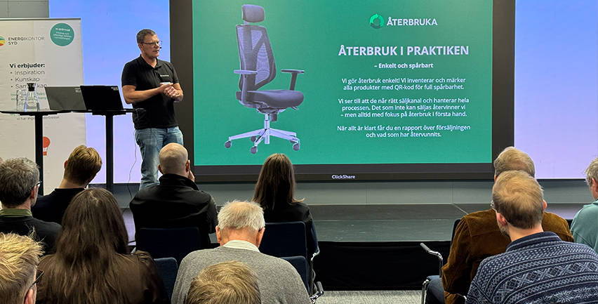 Foto på en man som håller en presentation framför publik. 