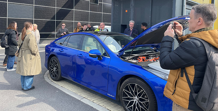 Människor runt en vätgasdriven bil.