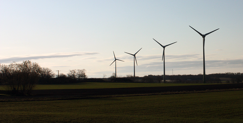 Foto på vindkraftverk i skymning. 