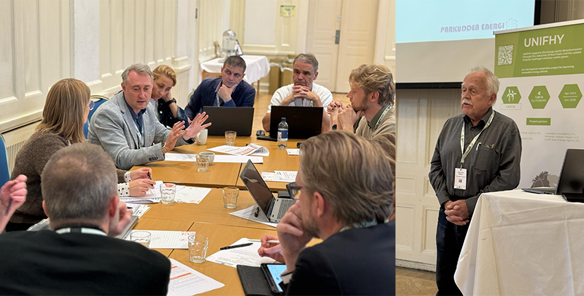 Människor som sitter runt ett bord. Till höger en äldre man framför en rollup.