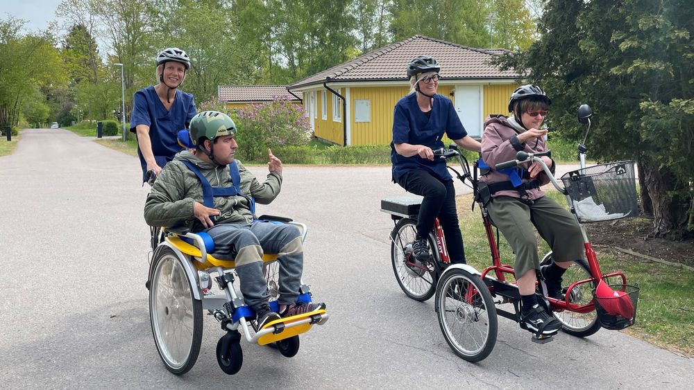 Personal och två brukare på varsin specialcykel på en villagata.