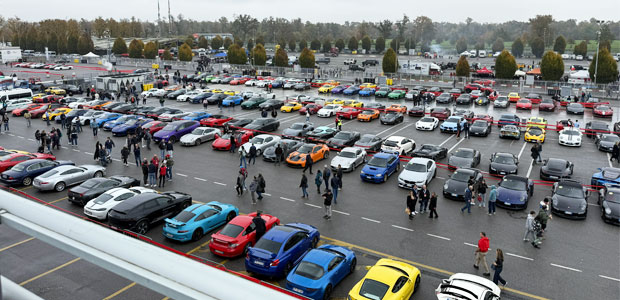 Bilden visar en stor parkeringsplats med ett hundratal sportbilar, bland annat flera bilar av märkena Porsche, Ferrari och Lamborghi.