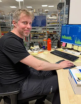 Marcus ler mot kameran när han sitter vid sin dator.