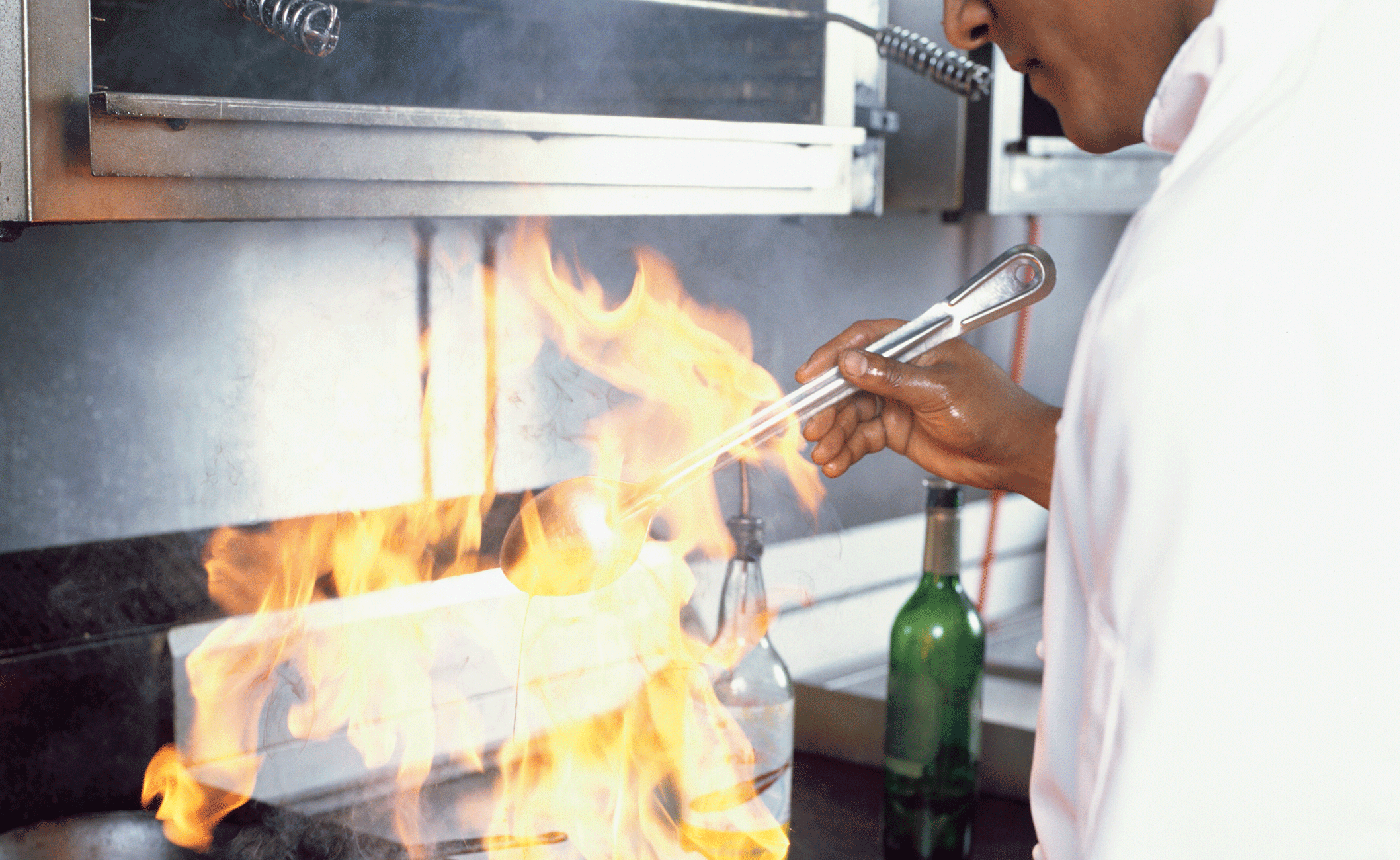 Kock i storkök som flamberar